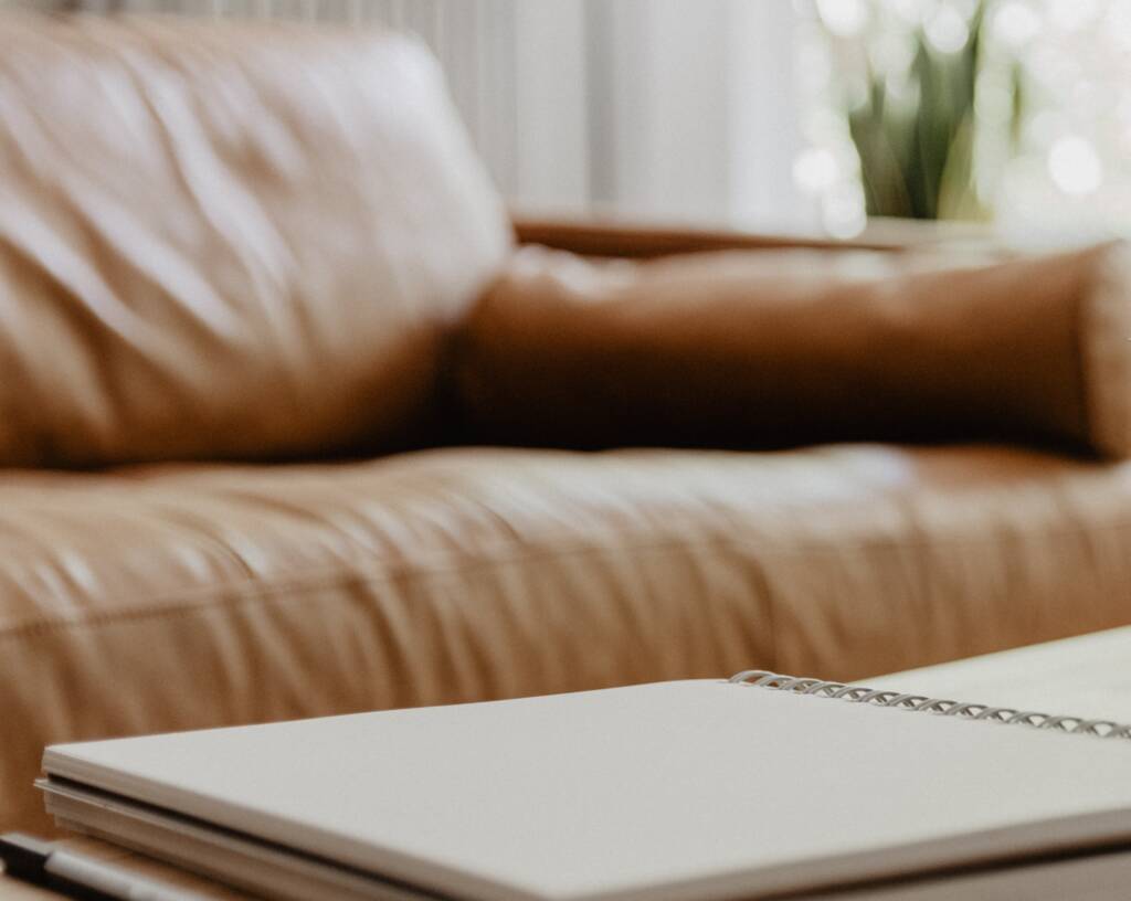 Close up of a brown leather sofa and notepad