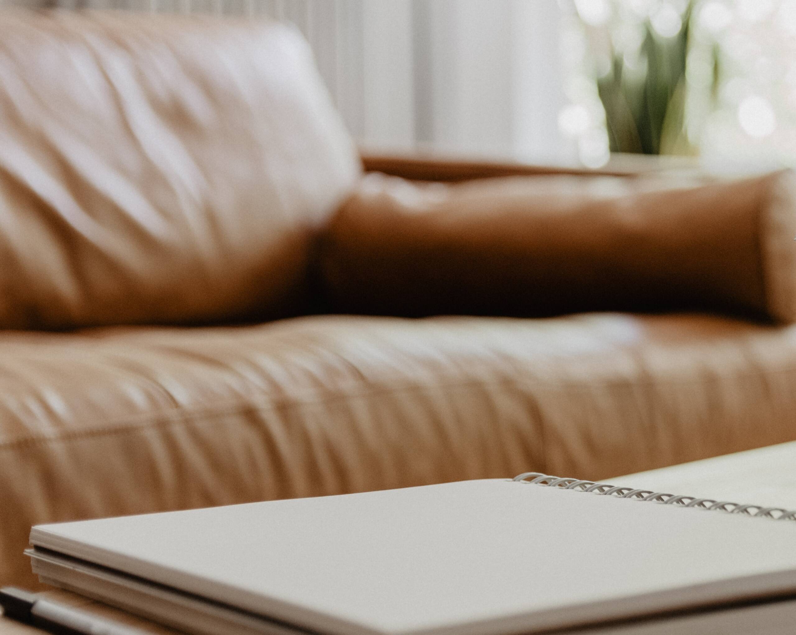 Close up of a brown leather sofa and notepad