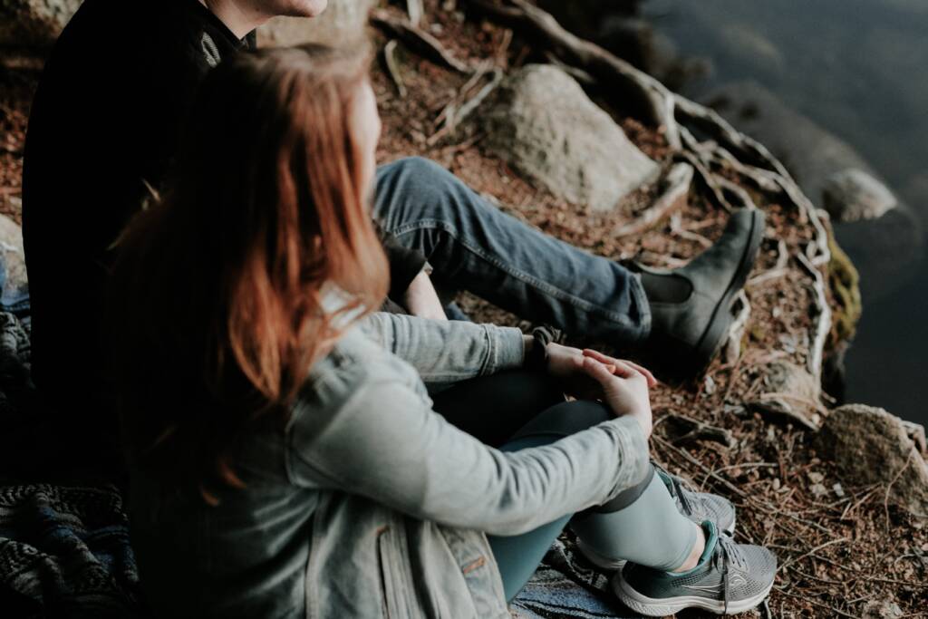 Man and women talking whilst sitting by water